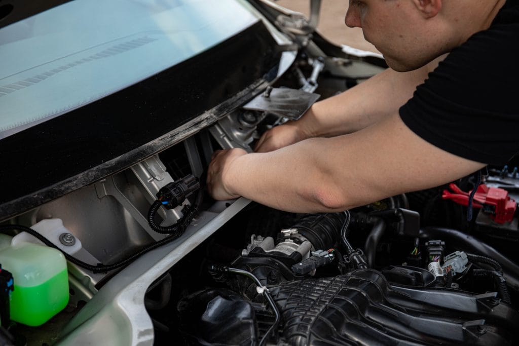 Mechanic performing pre-purchase inspection on a used ca