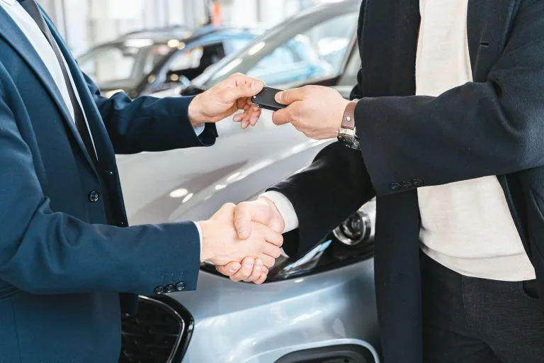 Illustration of a buyer and seller shaking hands over a used car deal, representing successful price negotiation