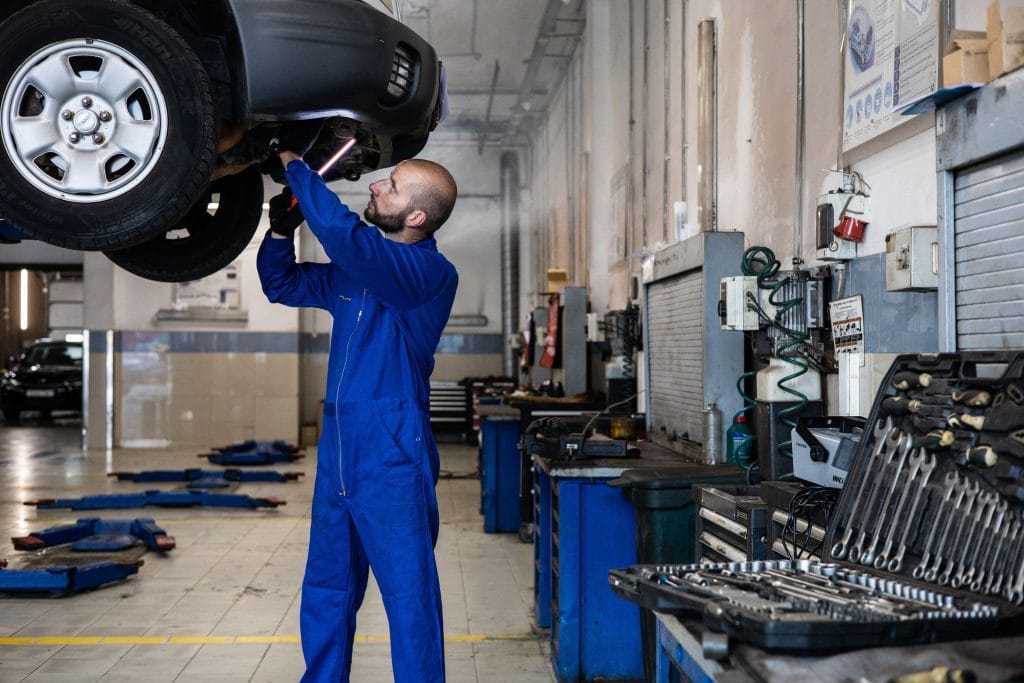 Mechanic inspecting a used car before the buyer starts to negotiate a used car price