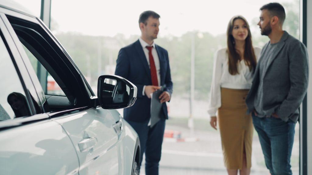 Buyer and seller discussing and negotiating the price of a used car at a dealership